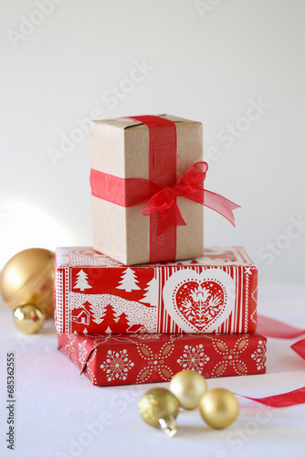 Pila di pacchetti regalo in versione natalizia di colore rosso con sullo sfondo palline di Natale e nastri