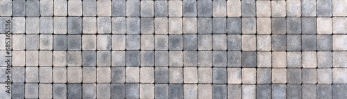 Gehweg aus viereckigen Pflastersteinen in verschiedenen beige und grau Farbtönen in Panorama Nahaufnahme photo