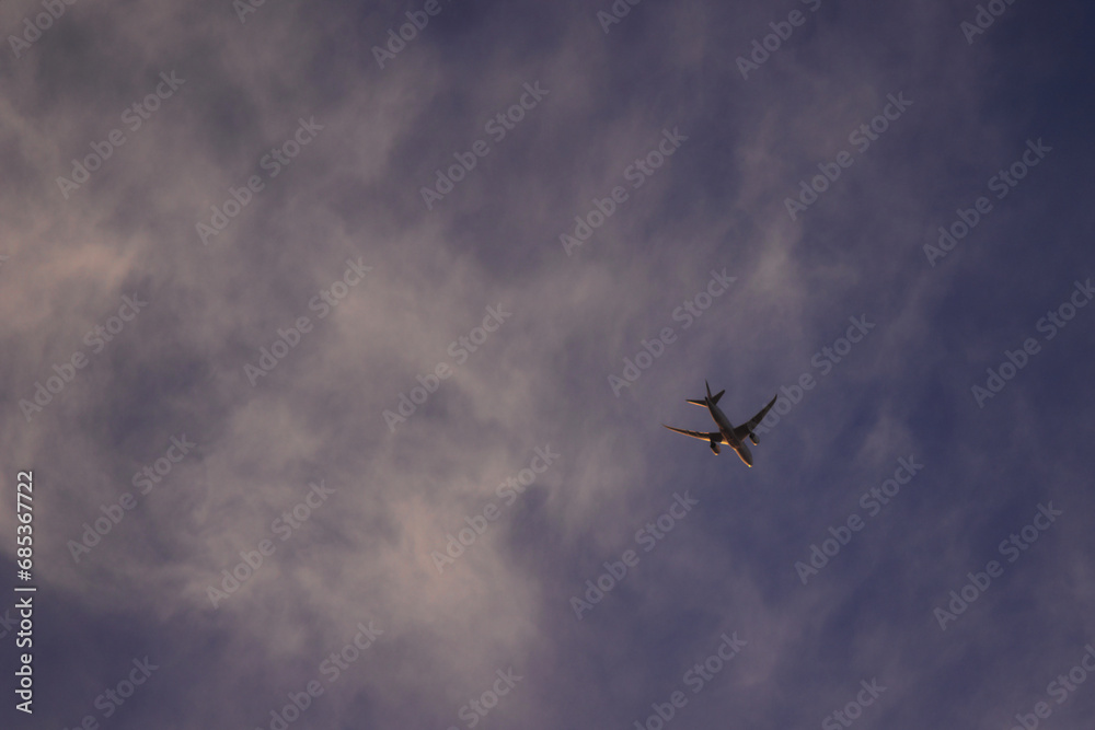 commercial jet airliner flying high under a blue sky covered by a thin sheet of clouds. commercial jet airliner flying high under a blue sky covered by a thin sheet of clouds.