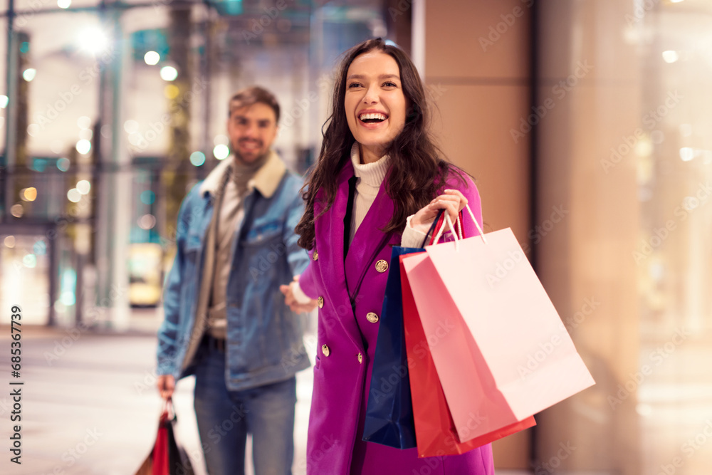 Joyful spouses walking near modern mall outdoor holding shopping bags Joyful spouses walking near modern mall outdoor holding shopping bags