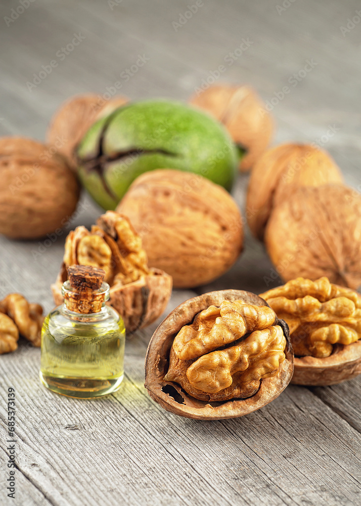 Walnut kernels, whole walnuts and bottles of essential nut oil on rustic wooden table. Healthy walnuts. Walnut kernels, whole walnuts and bottles of essential nut oil on rustic wooden table. Healthy walnuts.