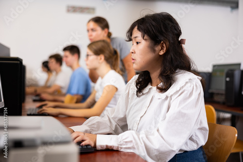Concentrated Asian female student using PC and studying computer science in the classroom