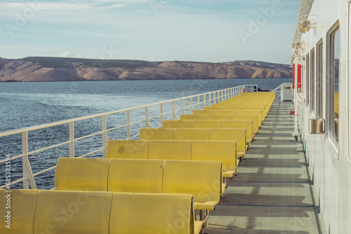 Typical ferry boat in croatia, connecting island of Pag to mainland. Classical yellow bench, noone visible due to low season. photo