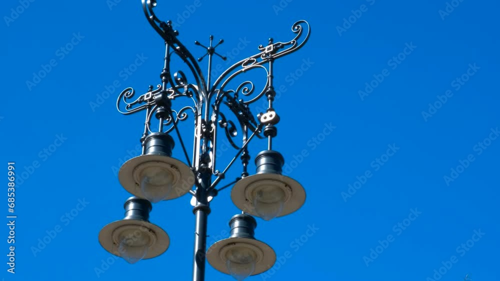 Iron street lamp against blue sky. A view of iron street lamps against blue sunny sky in the city street. Iron street lamp against blue sky. A view of iron street lamps against blue sunny sky in the city street.