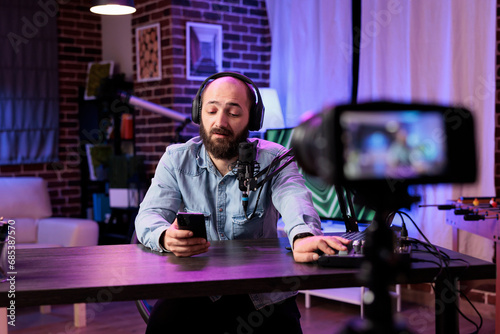 Content creator doing live broadcasting for online streaming service surprised by comments received from followers. Famous vlogger interacting with fans while recording in living room studio