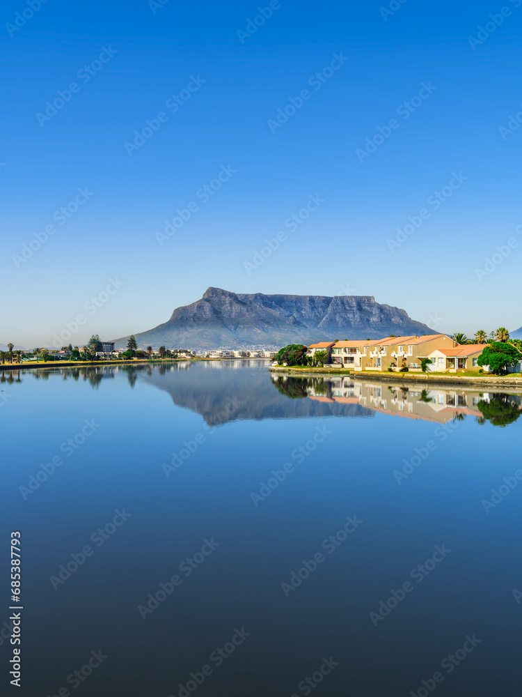 Vertical shot of the table mountain and its reflection in the woodbridge island lagoon during a clear day with blue sky, Cape Town South Africa