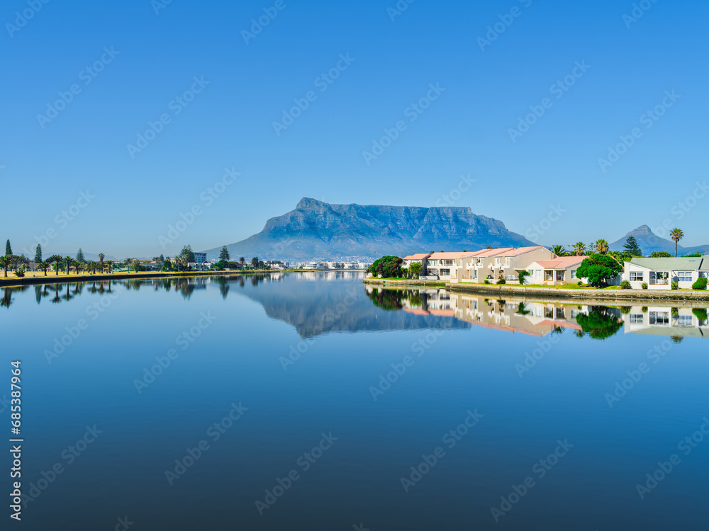 Table mountain and its reflection in the woodbridge island lagoon during a clear day with blue sky, Cape Town South Africa
