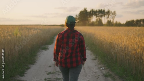 View from the back of an agronomist walking across a field with a tablet