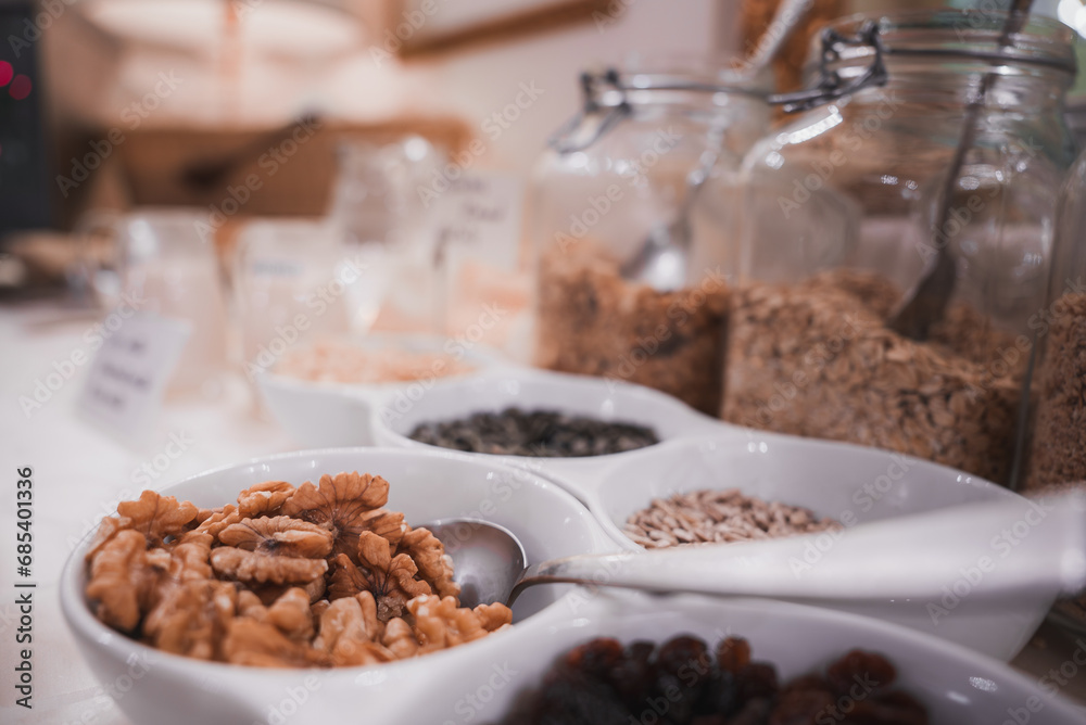 A variety of cereal, nuts, and granola in bowls and jars arranged in a horizontal line. Beautiful and delicious breakfast setup in Venice, Italy. A variety of cereal, nuts, and granola in bowls and jars arranged in a horizontal line. Beautiful and delicious breakfast setup in Venice, Italy.
