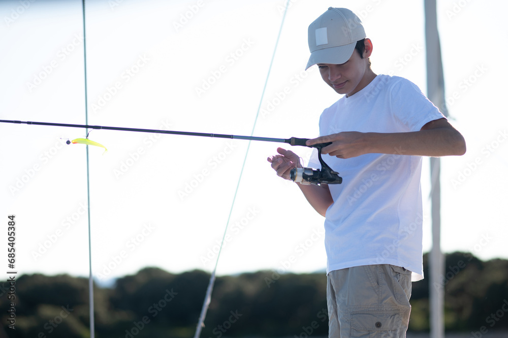 Young guy in white with a fishing rod on the yacht Young guy in white with a fishing rod on the yacht