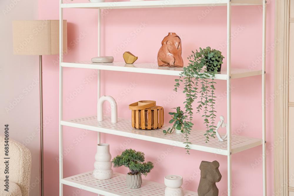 Fototapeta premium Modern shelf unit and lamp near pink wall