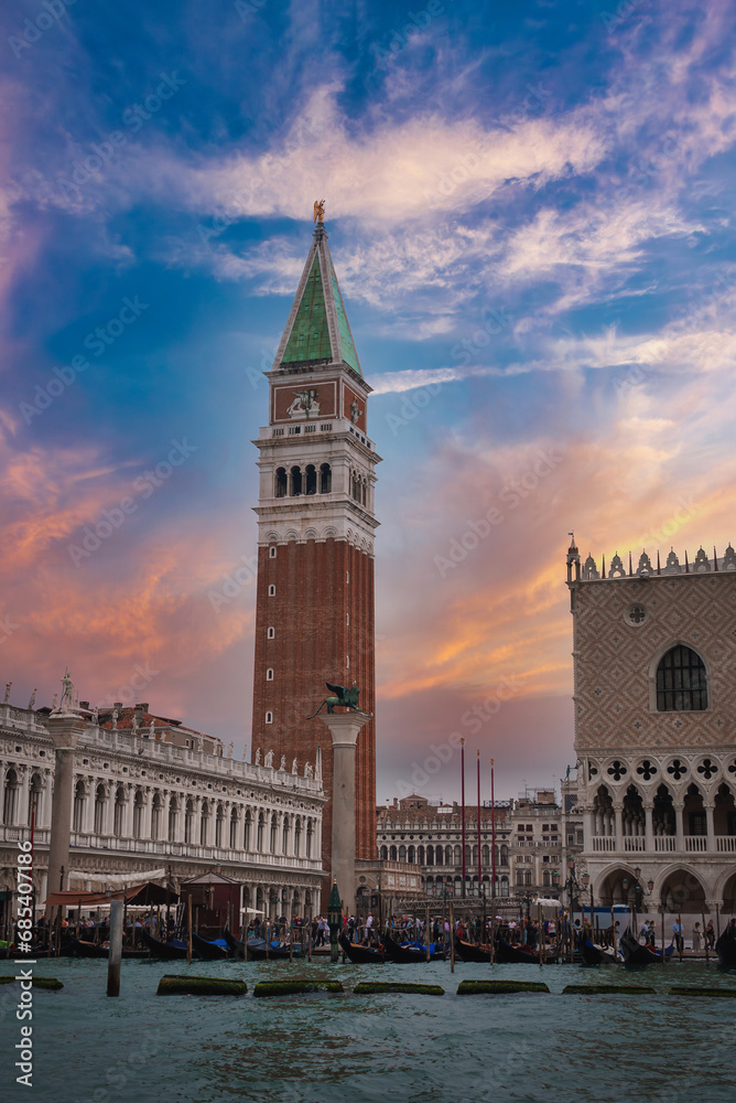 Aerial view of Venice, Italy with a clock tower in the background. The photo captures the city's architecture and waterways, showcasing the timeless allure of Venice.