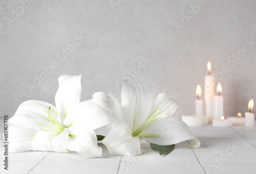 Beautiful lily flowers with burning candles on table