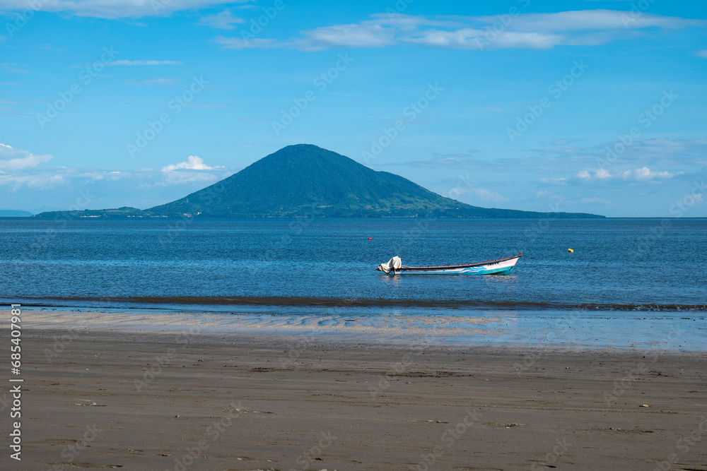 Volcanic Island, Boat and Beach with Lush Vegetation Forest Around Beautiful and Calm Ocean