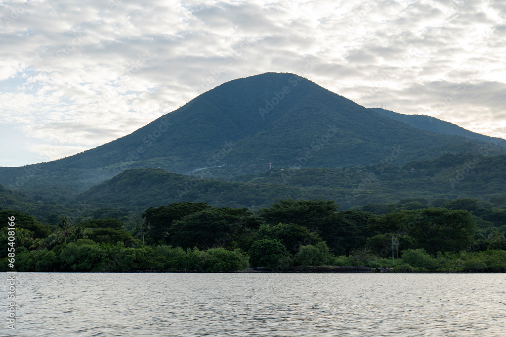 Coastline Seen From Afar with a Volcanic Mountain, Lush Vegetation Forest and Some Electric Lines and Poles with a Calm Ocean