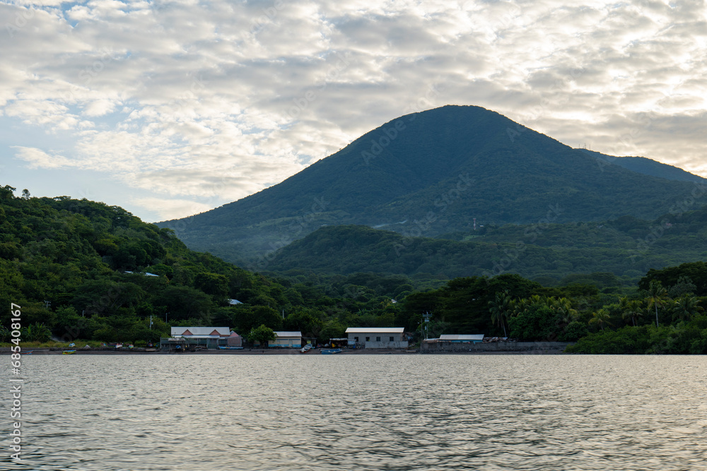 Coastline Seen From Afar with a Volcanic Mountain, Lush Vegetation Forest, Beach, and Houses with a Calm Ocean