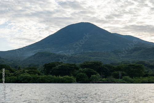 Obraz na płótnie Coastline Seen From Afar with a Volcanic Mountain, Lush Vegetation Forest and Some Electric Lines and Poles with a Calm Ocean w salonie