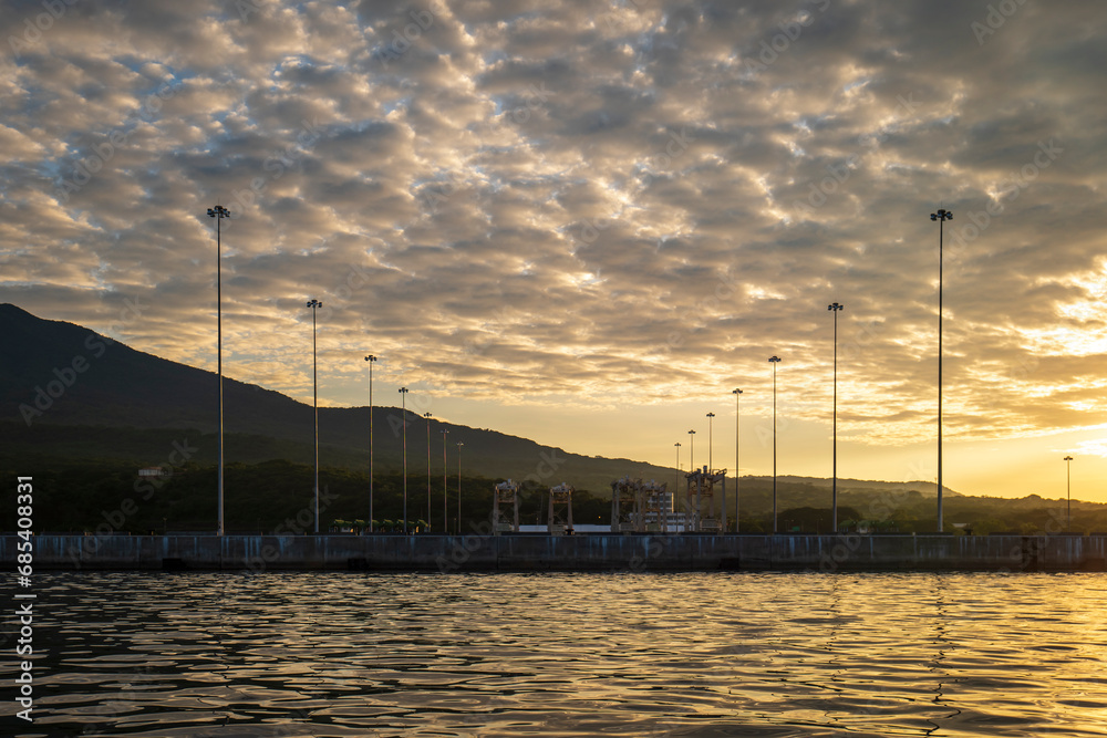 Industrial Seaport with Several Light Poles at a Bright Yellow Sunset