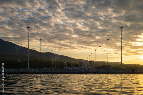 Obraz na płótnie Industrial Seaport with Several Light Poles at a Bright Yellow Sunset w salonie