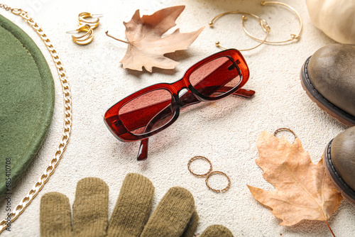 Composition with stylish female accessories and autumn leaves on light background