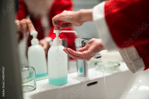 Woman Santa Claus Wash and disinfect her Hands in Bathroom before going on Christmas Eve