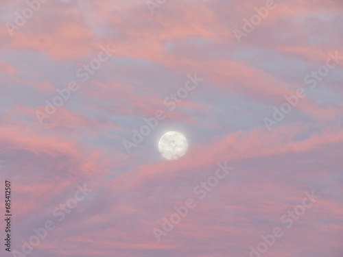 Full moon with light blue sky and pink and purple clouds