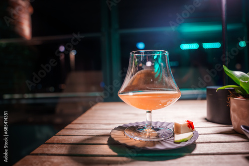 A cozy and intimate atmosphere is captured in this close-up of a full wine glass on a wooden table at night. Perfect for Venice-themed luxury restaurant or hotel content. photo