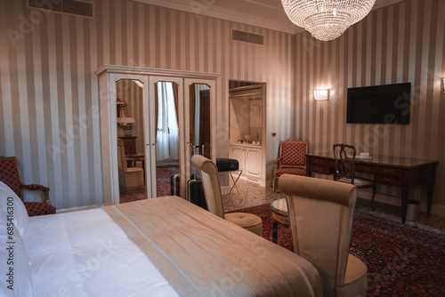Experience the elegance of Hotel Savoy in Venice, Italy with a sophisticated king-sized bed and stylish chair in this luxurious hotel room. photo