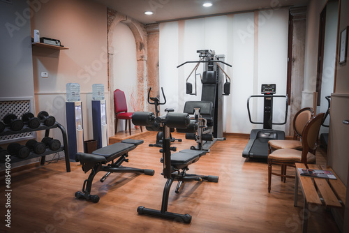 Modern gym room with exercise equipment including a rowing machine, captured from a side angle. No flooring or windows are visible. photo