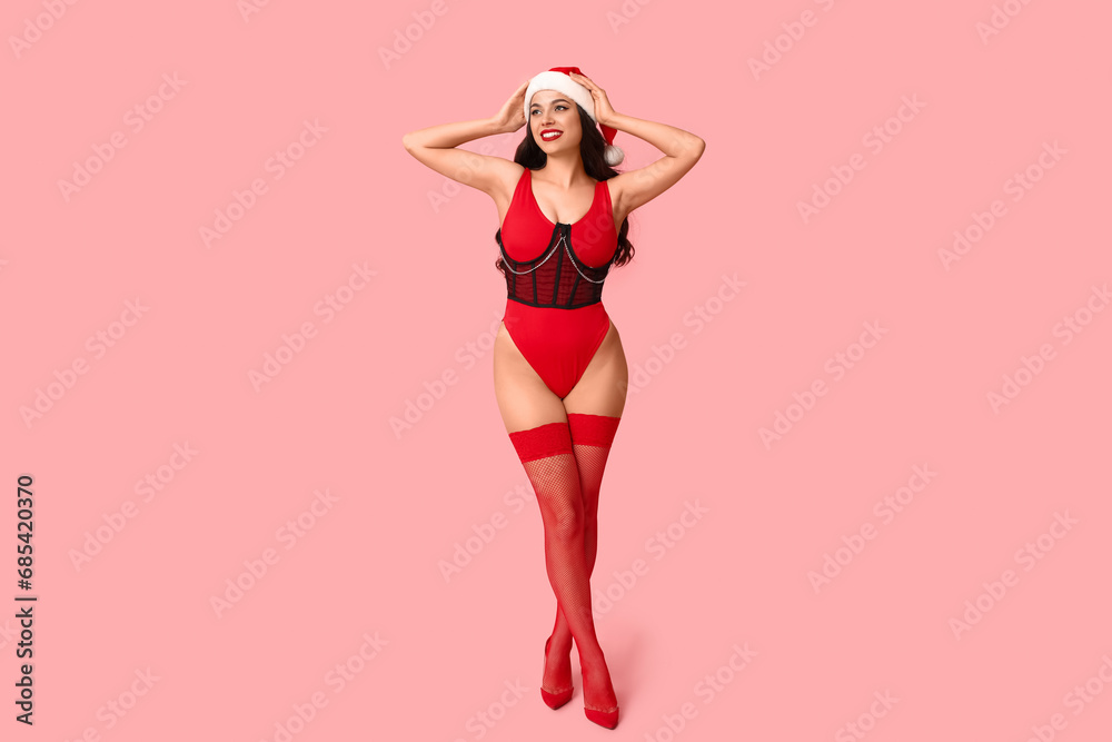 Beautiful young sexy woman in corset and Santa hat on pink background - obrazy, fototapety, plakaty 
