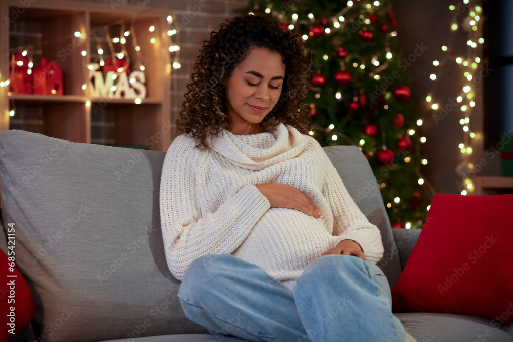 Pregnant African-American woman sitting at home on Christmas eve Pregnant African-American woman sitting at home on Christmas eve