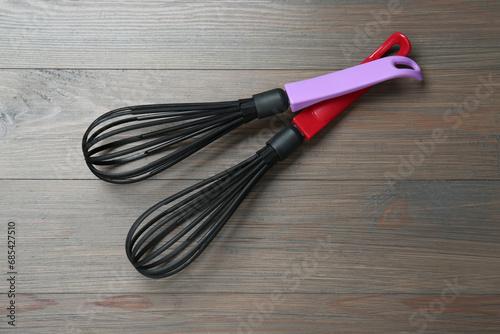 Two whisks on wooden table, top view. Kitchen tool