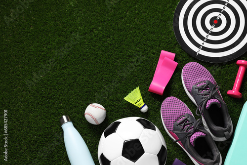 Different sports equipment on green grass, flat lay. Space for text