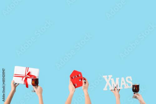 Female hands with glasses of warm mulled wine and Christmas decor on blue background