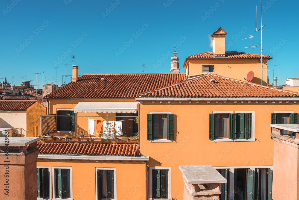 Aerial view of vibrant orange building in Venice, Italy. Architectural style not clear, likely near water. Captures beauty and charm of Venice in summer.