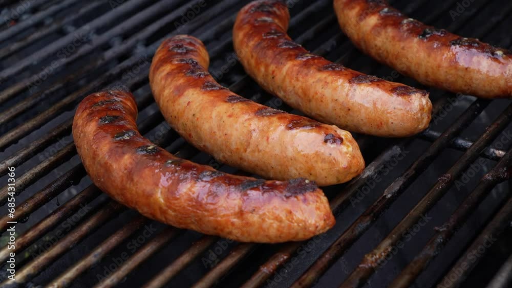 Grilled BBQ meat sausages on stainless grill with fire flames close up. Food and cuisine concept. Grilled BBQ meat sausages on stainless grill with fire flames close up. Food and cuisine concept.