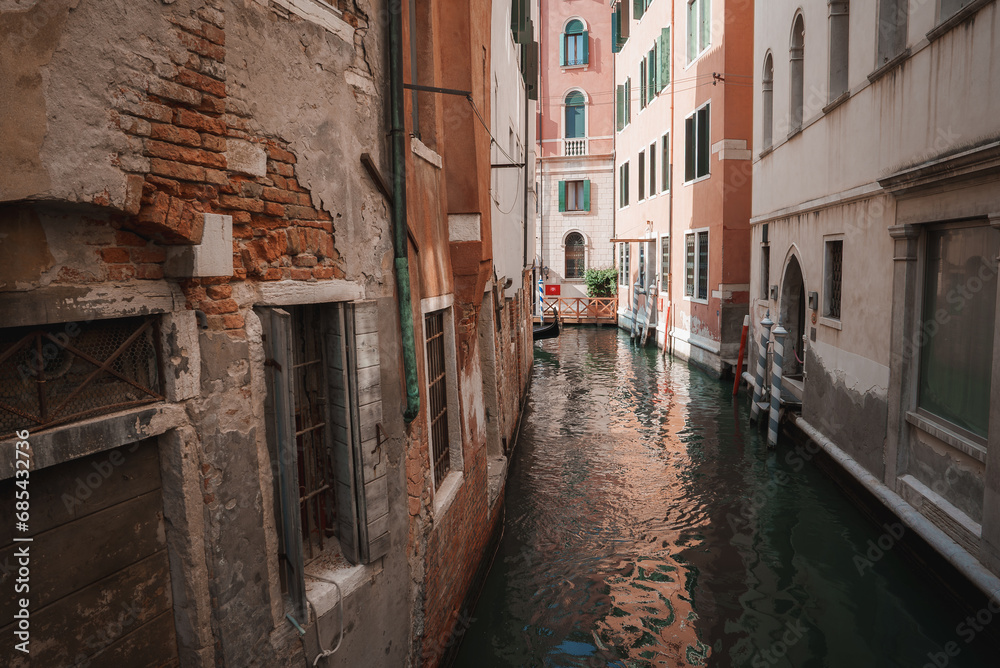 A serene and picturesque view of a narrow canal in Venice, Italy. The straight-on angle showcases the tranquil atmosphere of this iconic scene.