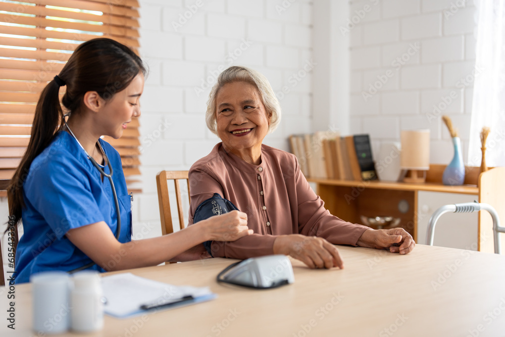 Asian caregiver doctor examine older patient use blood pressure gauge.