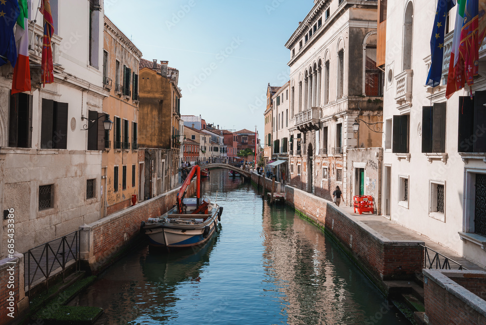 Scenic narrow canal in Venice, Italy with traditional architecture and boats. Serene waterway with no landmarks visible. Ideal for travel, tourism, and vacation concepts.