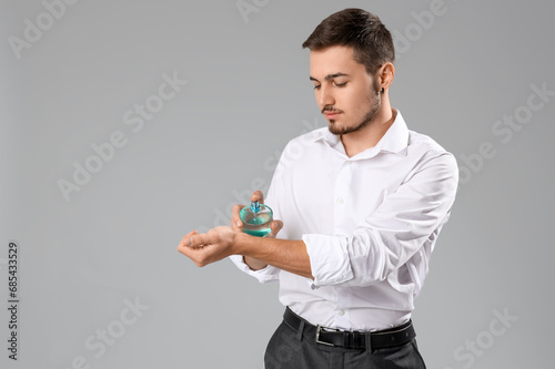 Handsome man applying perfu...