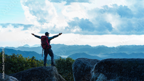 Asian Male Hiker cheering elated and blissful with arms raised in the sky after hiking. Mueang haeng camping ground, Chiang mai, Thailand.