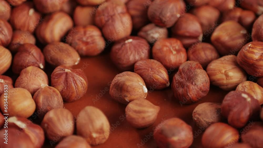 Peeled hazelnut on red plate close-up macro. Hazelnuts without shell. Man hand take some nuts. Product rich in minerals and vitamins. Healthy snacks. Peeled hazelnut on red plate close-up macro. Hazelnuts without shell. Man hand take some nuts. Product rich in minerals and vitamins. Healthy snacks.