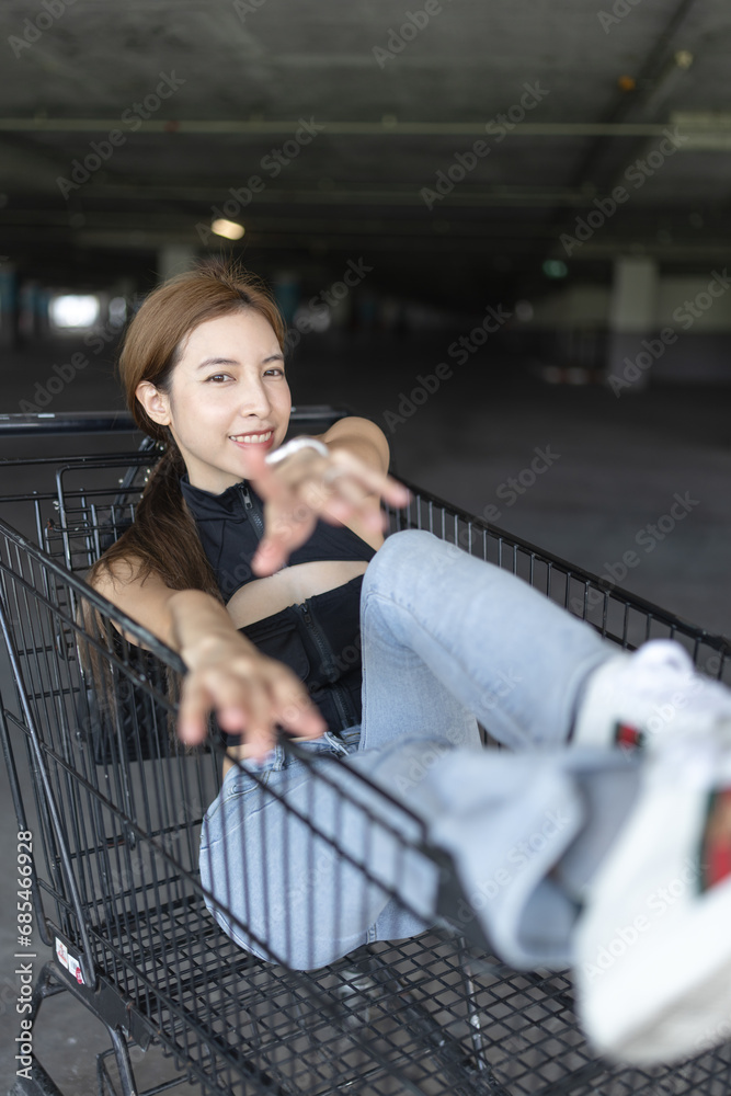 Young woman sitting in shopping cart.