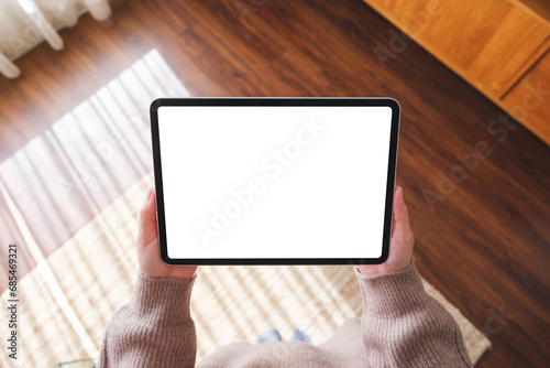 Top view mockup image of a woman holding digital tablet with blank desktop screen at home