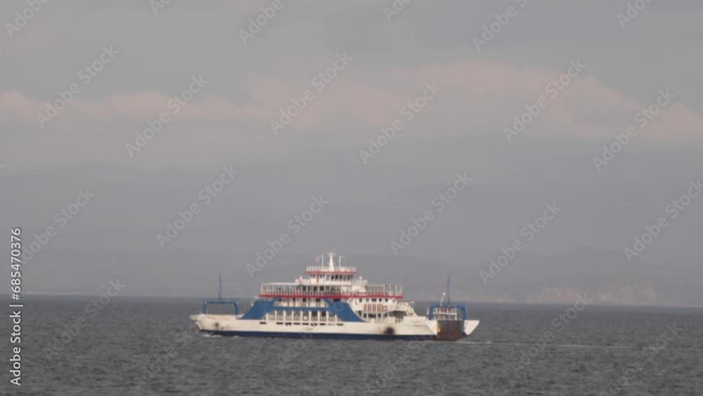 White and blue ferry boat transporting passengers, cargo, and vehicles, across the Pacific Ocean on a sunny day in the Gulf of Nicoya, Costa Rica. White and blue ferry boat transporting passengers, cargo, and vehicles, across the Pacific Ocean on a sunny day in the Gulf of Nicoya, Costa Rica.