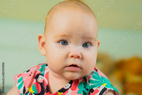 Portrait of a cute little baby girl in a colorful shirt.