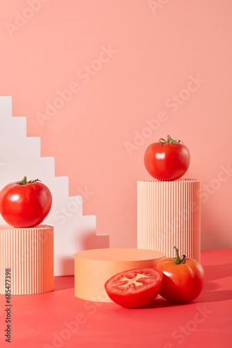 Front view of creative pink background with tomatoes and different size platforms. Ideal display space for natural cosmetics or vegan products. photo