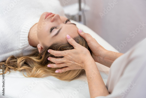 Healer performing by lightly touched access bars therapy on young woman head, stimulating positive change thoughts and emotions. Alternative medicine concept photo