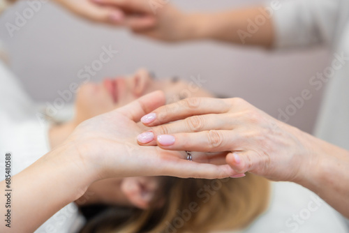 Close up view of healer launches body energy through hands before access bars therapy with young woman, stimulating positive change thoughts and emotions. Alternative medicine concept.