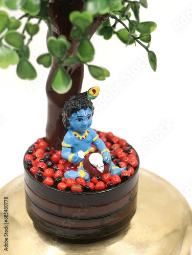 Photography a colorful doll statue of cute baby sri krishna in blue eating butter out of a p